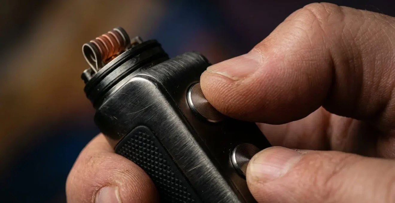 Gros plan sur les mains d'un vapoteur ajustant les réglages d'une box électronique moderne
